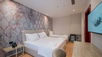 A hotel room with a large bed, a desk with a chair, a telephone, and a TV on the wall.