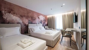 Une chambre d’hôtel avec deux lits, un bureau et une télévision.