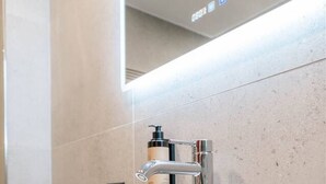Une salle de bain moderne avec un grand lavabo blanc, un robinet chromé et un miroir au-dessus.