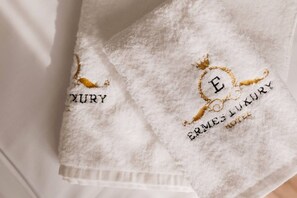 Two white towels with embroidered text and a crown symbol. - Ermes Deluxe Triple Room with Balcony and Sofa Bed (Durrës)