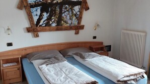 A bedroom with a wooden bed, a wall-mounted picture frame, bedside tables, and a hanging light fixture.