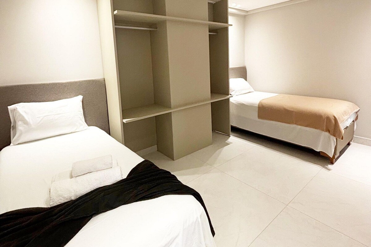 Ein Hotelzimmer mit zwei Betten, einem Kleiderschrank und einem Nachttisch.