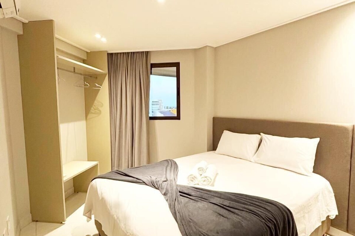 Ein Hotelzimmer mit Bett, Schrank, Spiegel und Fenster mit Blick.