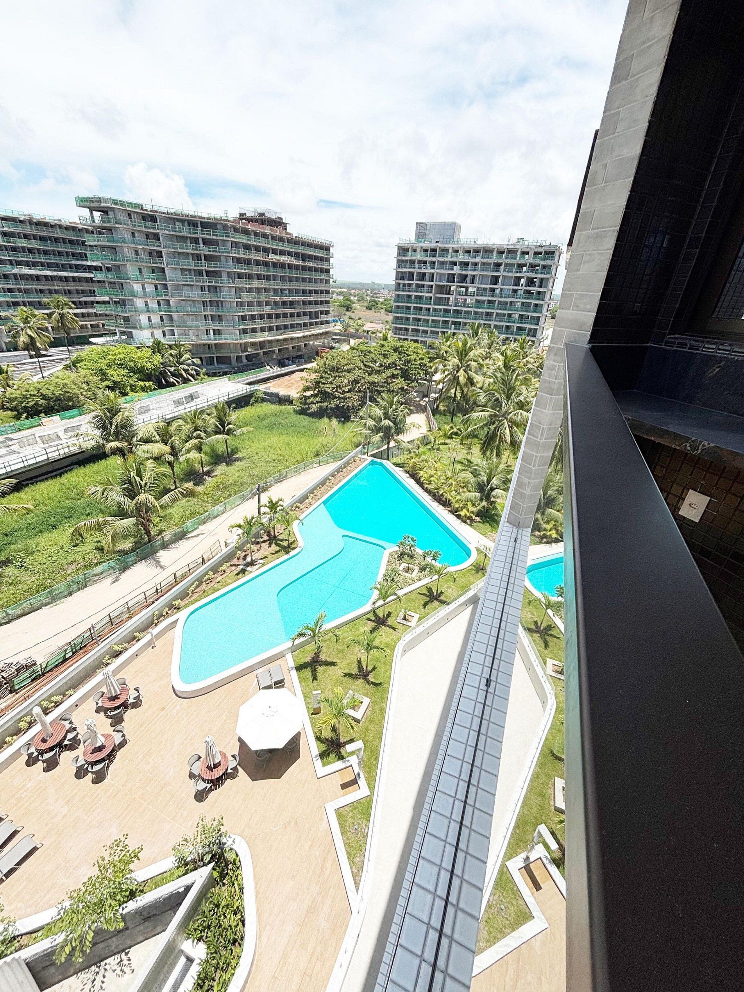A high-rise building with a rooftop pool and outdoor seating area.