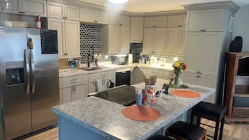 A modern kitchen with a stainless steel refrigerator, a built-in microwave, and a granite countertop.