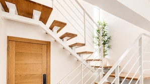 A modern staircase with wooden steps and white railings, leading to a door with a wooden panel design. - Caribbean getaway,  minutes away from the airport,  Downtown Punta Cana, beaches and attractions. Whether you're here for adventure, romance, great family time or pure relaxation, this is the place where memories are made. (Punta Cana)