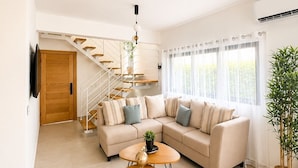 A modern living room with a sofa, coffee table, and staircase. - Caribbean getaway,  minutes away from the airport,  Downtown Punta Cana, beaches and attractions. Whether you're here for adventure, romance, great family time or pure relaxation, this is the place where memories are made. (Punta Cana)
