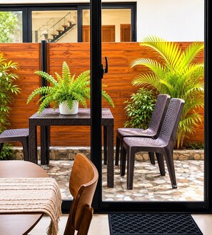 Un área de estar al aire libre con una mesa, sillas y plantas en macetas.