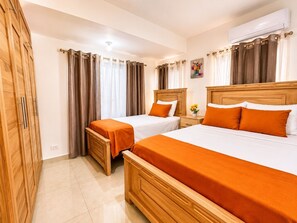 Habitación de hotel con dos camas, un armario y un equipo de aire acondicionado.