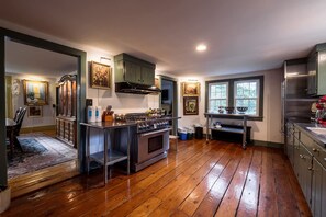 Una cocina amplia con suelo de madera, una isla central y armarios verdes.