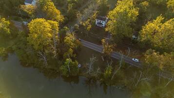 An aerial view of a residential area with a road, a house, and surrounding trees.
