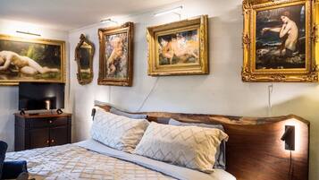 Un dormitorio con una cama grande, un cabecero de madera y tres cuadros en la pared.
