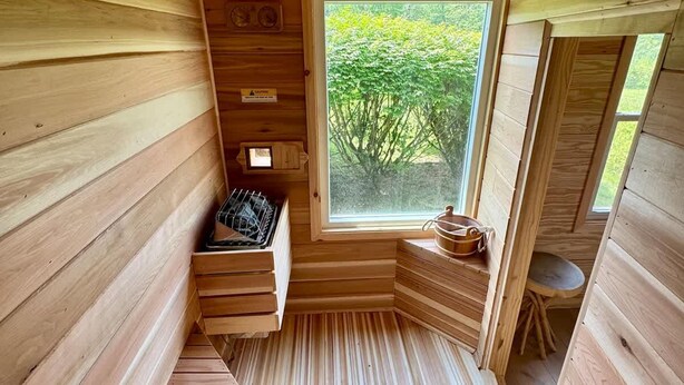 A wooden sauna with a window, a bench, and a small table.