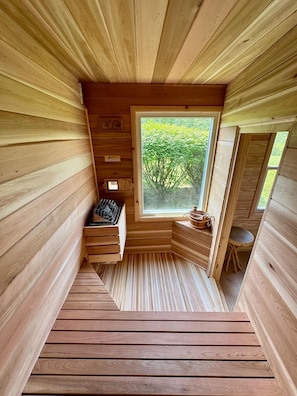 Una sauna de madera con ventana, banco y una pequeña mesa.