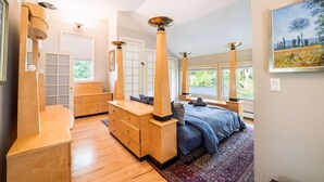 A bedroom with a large bed, wooden furniture, and tall columns.