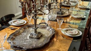 A dining table set with candles, silverware, and glassware, with a chandelier above.