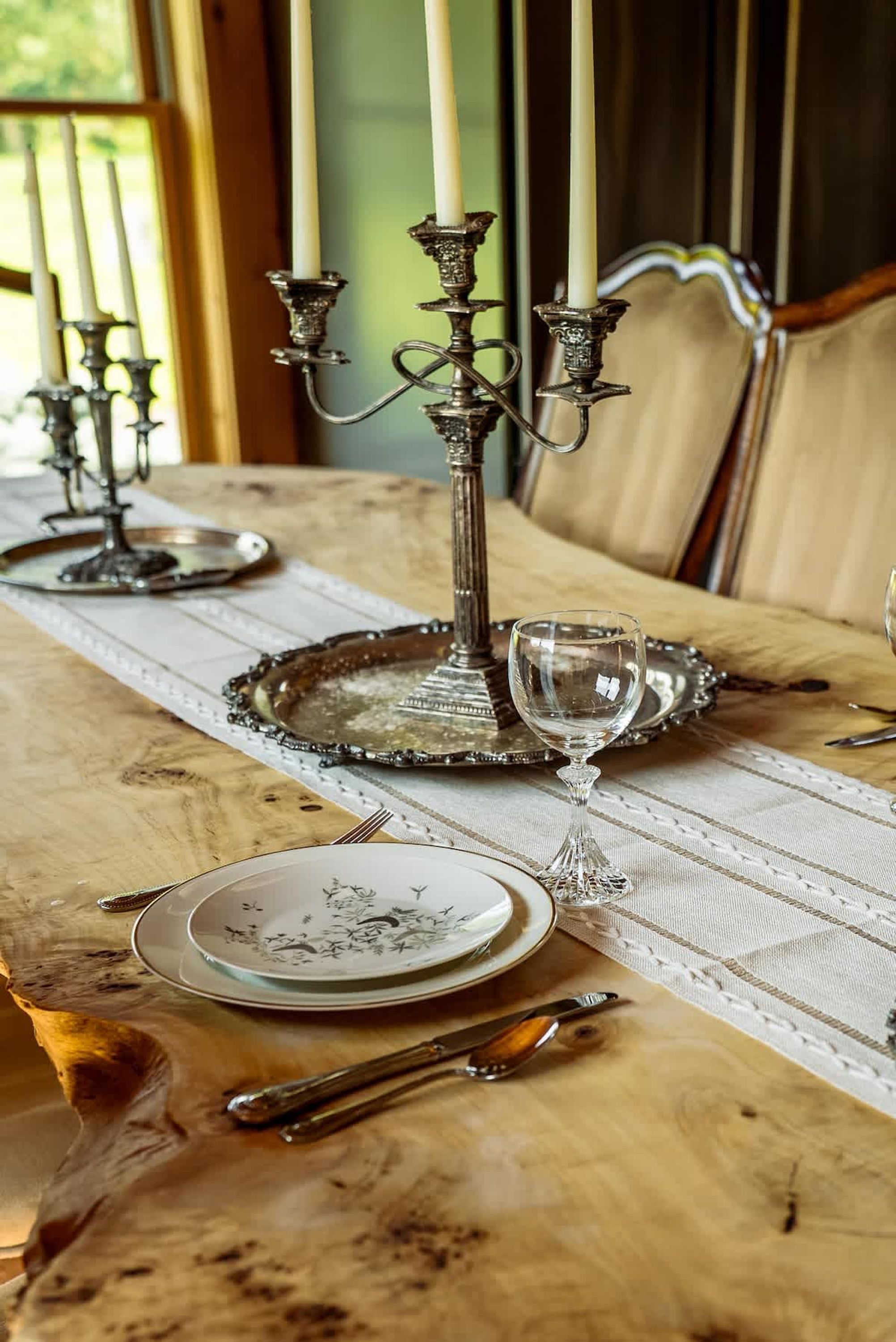 Une table à manger dressée avec des assiettes, des couverts, un verre et un chandelier.