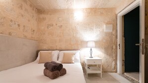 A hotel room with a bed, a nightstand with a lamp, and a door. - Valletta Exclusive 3BR House with Rooftop Terrace (Valletta)
