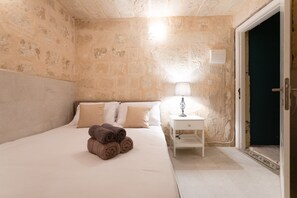 A hotel room with a bed, a nightstand with a lamp, and a door. - Valletta Exclusive 3BR House with Rooftop Terrace (Valletta)