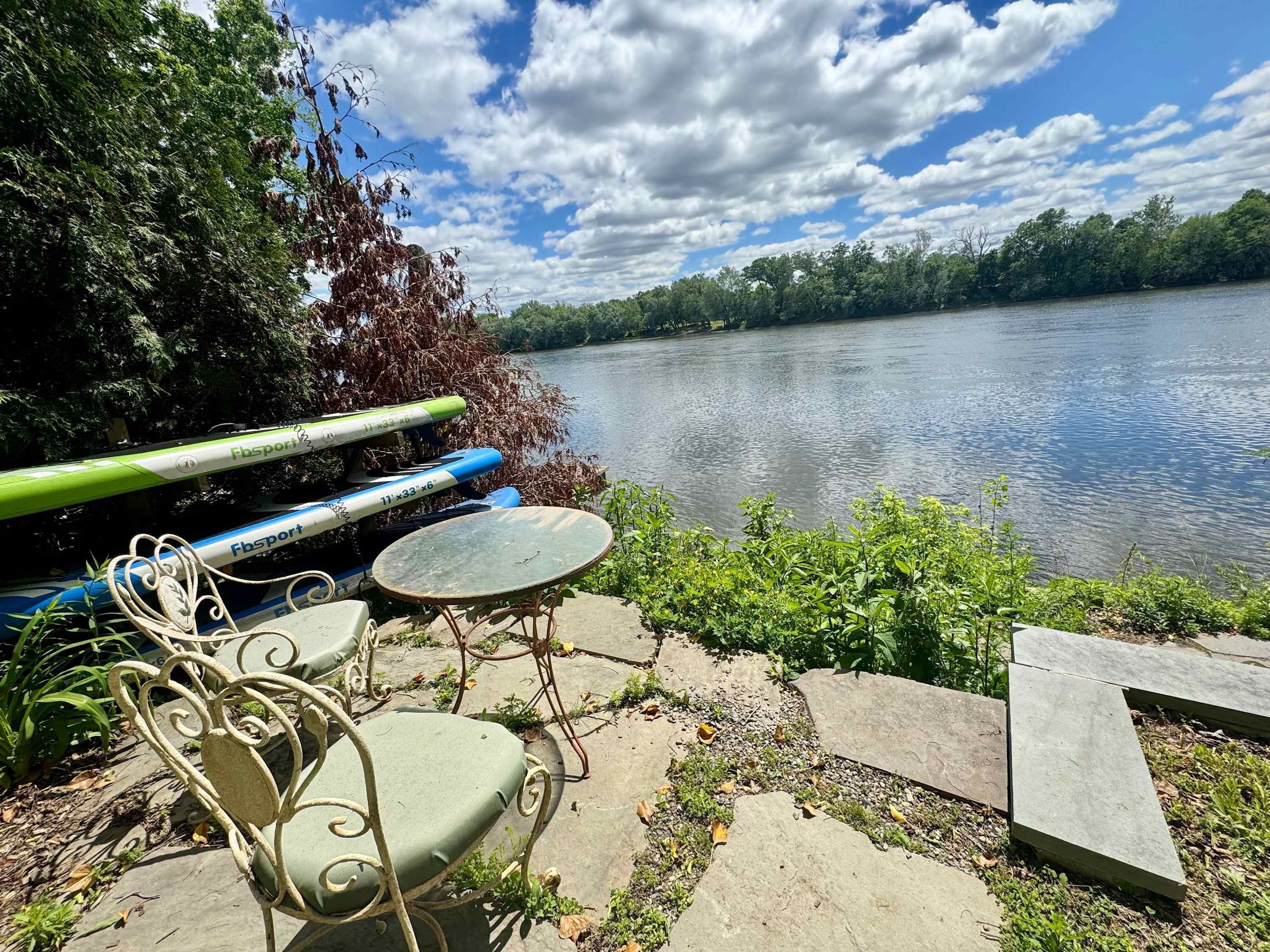 A lakeside patio with outdoor seating, a table, and a kayak.