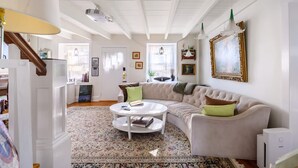 A living room with a white sofa, a round coffee table, and a patterned rug. - Charming   Whimsical Historic River Home (Hopewell Township)