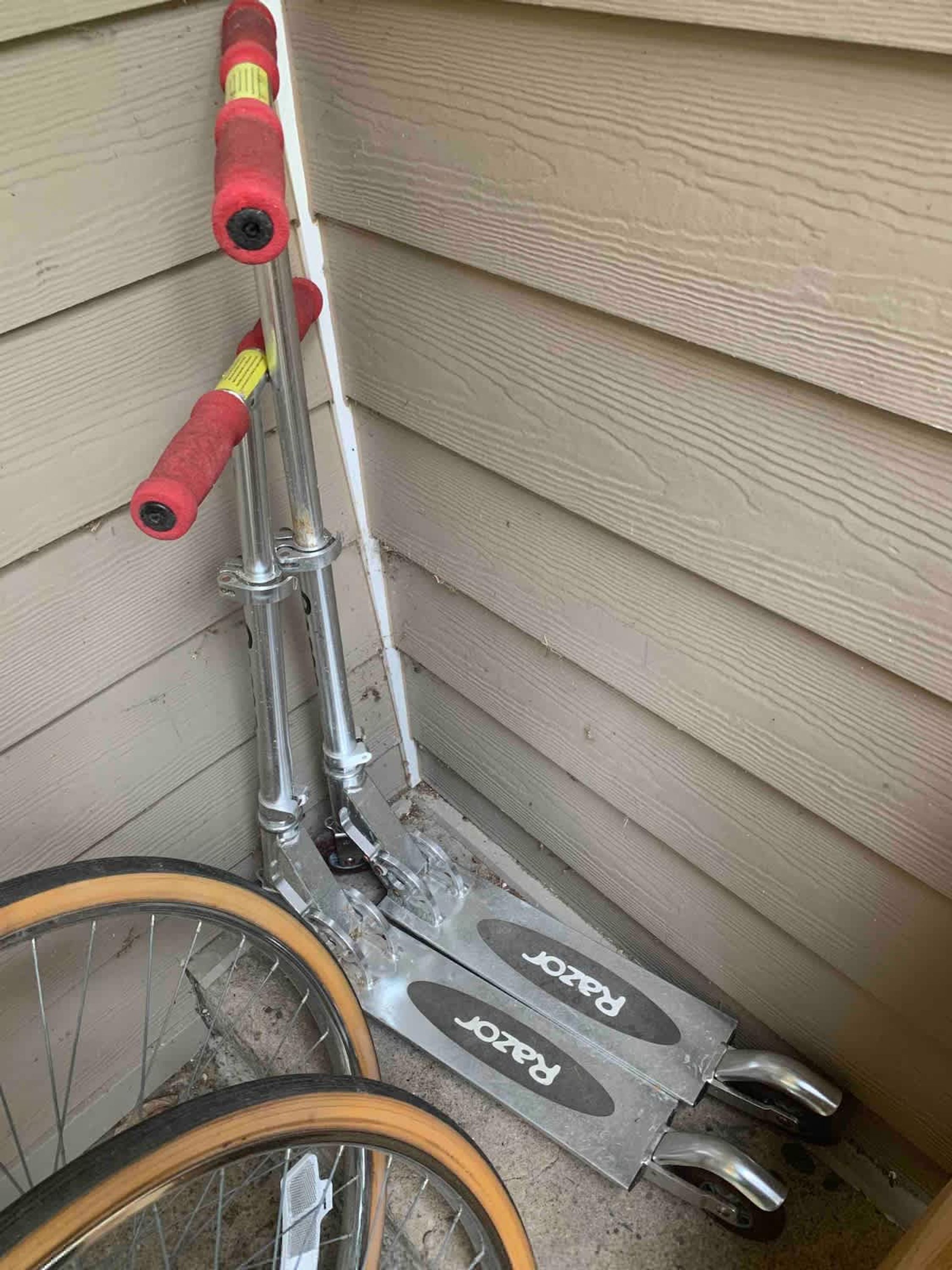 Un vélo avec un guidon rouge et un cadre en métal, appuyé contre un mur en bois.