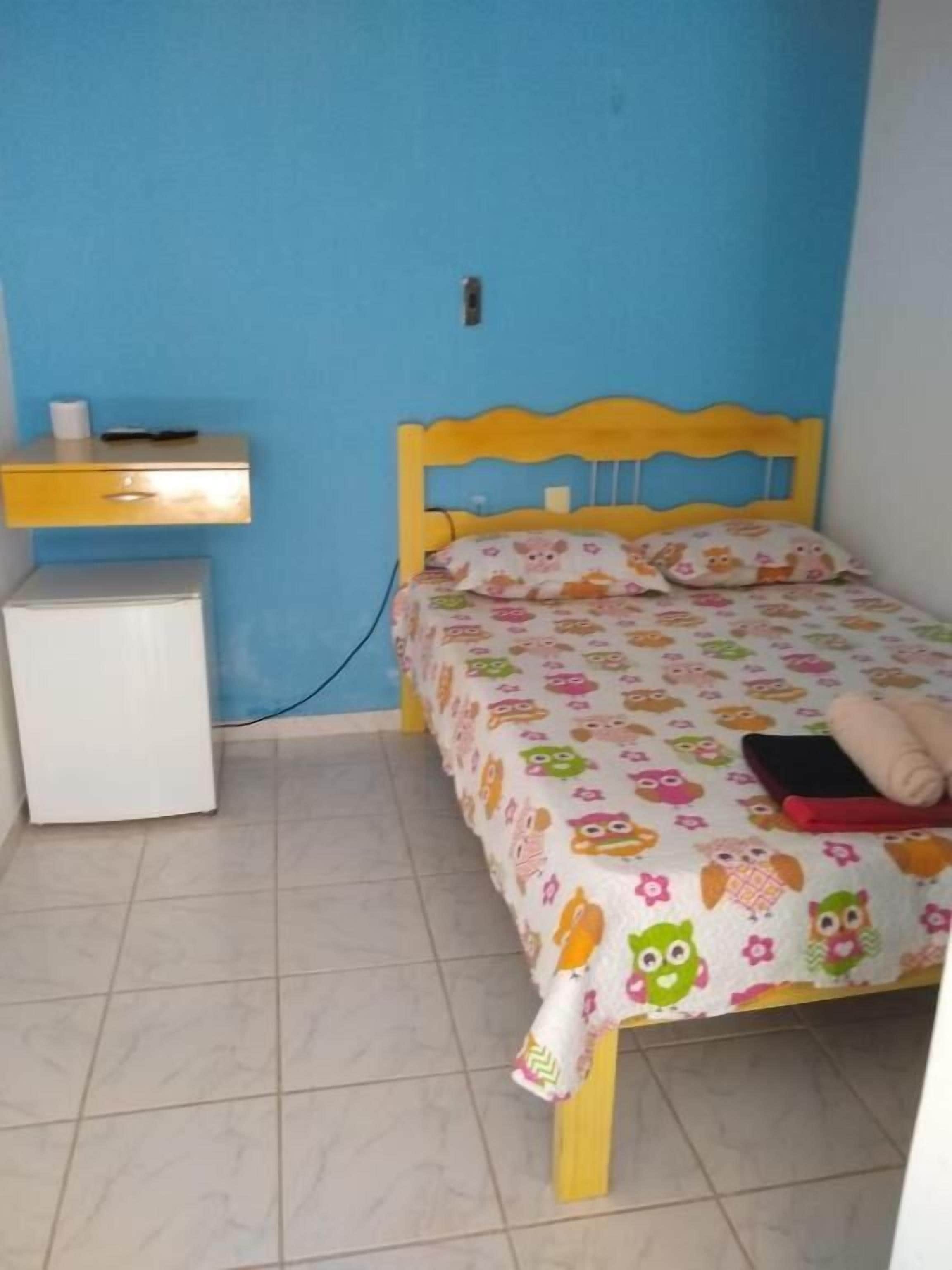 A bedroom with a bed, a nightstand, and a small white cabinet.
