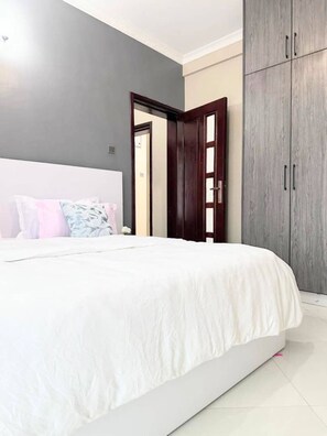 Un dormitorio con una cama grande, un armario y una puerta que da a otra habitación.