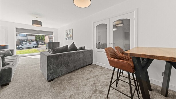 Un salon moderne avec un canapé gris, une table à manger en bois et une chaise noire.