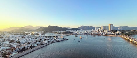 A coastal cityscape with a marina, buildings, and mountains in the background.