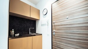 Una cocina compacta con microondas, pileta, alacenas, un reloj y una puerta de madera.