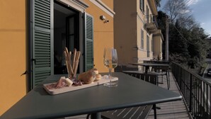 Una mesa con comida y una copa de vino en un balcón con vistas a un edificio.