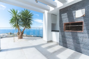 A balcony with a view of the sea, a palm tree, and a stone wall. - Villa Vista Atlântica by Atlantic Holiday (Ribeira Brava)