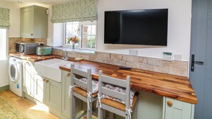 A kitchen with a washing machine, a TV, and a wooden counter. - Frog Leap (Scunthorpe)