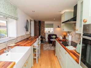 A compact kitchen with a wooden countertop, a built-in stove, and a small dining area with a chair and table. - Frog Leap (Scunthorpe)