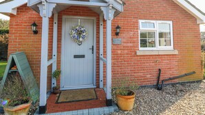 A brick cottage with a white door, a small window, and a sign reading 'Frog Leap Cottage.' - Frog Leap (Scunthorpe)