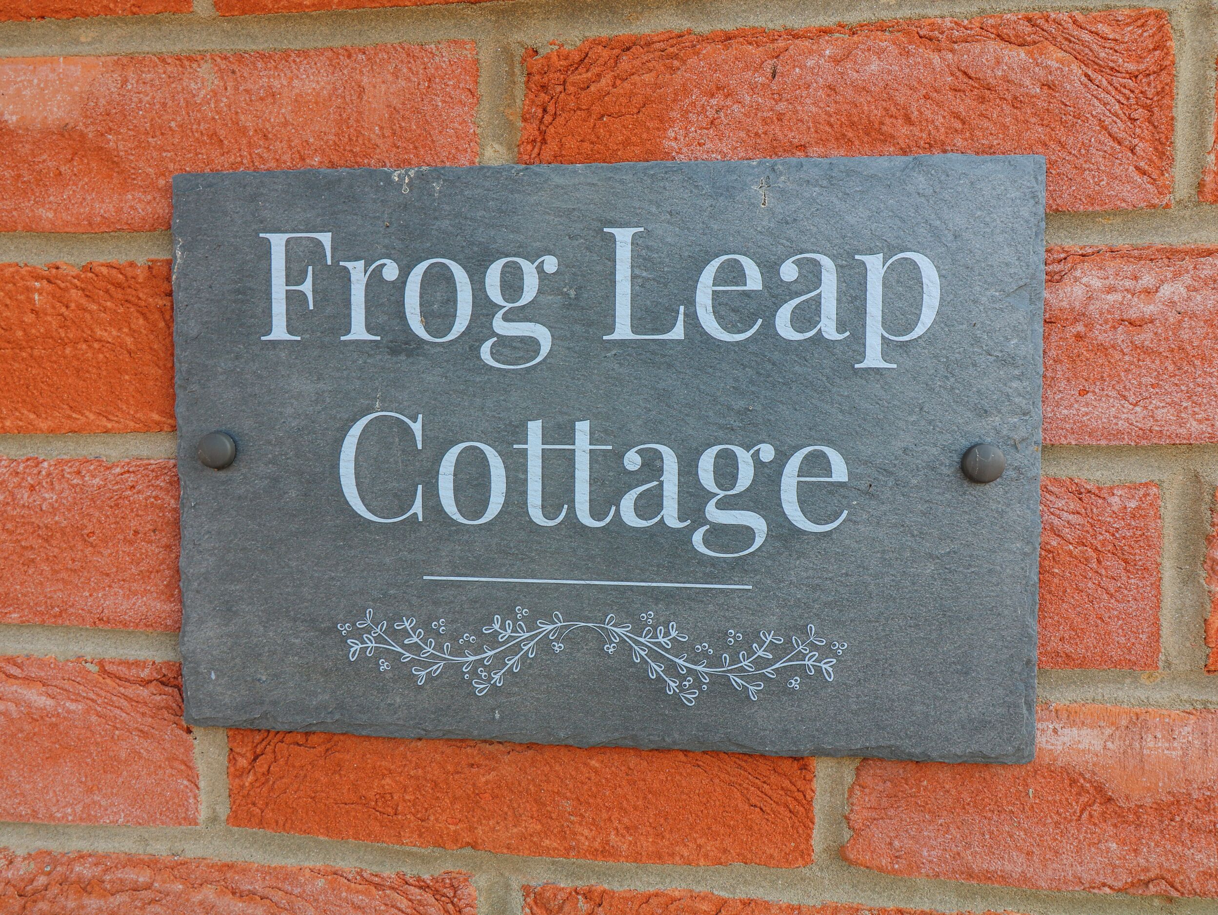 Egy palatáblából készült tábla, melyen a „Frog Leap Cottage” felirat szerepel, és egy téglából épült falra van rögzítve.