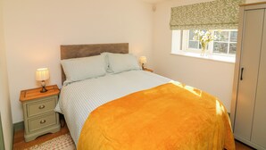 A bedroom with a bed, bedside tables, a window with a view, and a wardrobe. - Frog Leap (Scunthorpe)