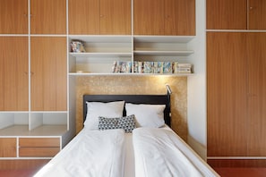 Ein Schlafzimmer mit einem Bett, einem Holzschrank und Regalen mit Büchern.