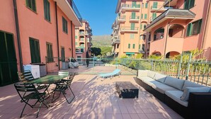 A courtyard with outdoor furniture, a pool, and multi-story buildings with balconies. - Terrazza vicino alla spiaggia in centro (Marina di Andora)
