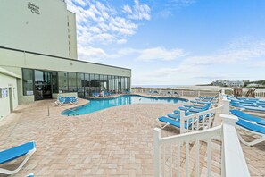 A pool area with blue lounge chairs and a building labeled "Sanda Beach Club". - Seashells & Sand Traps
Oceanfront 2BR Condo - Stunning Views & Steps to Beach (Myrtle Beach)