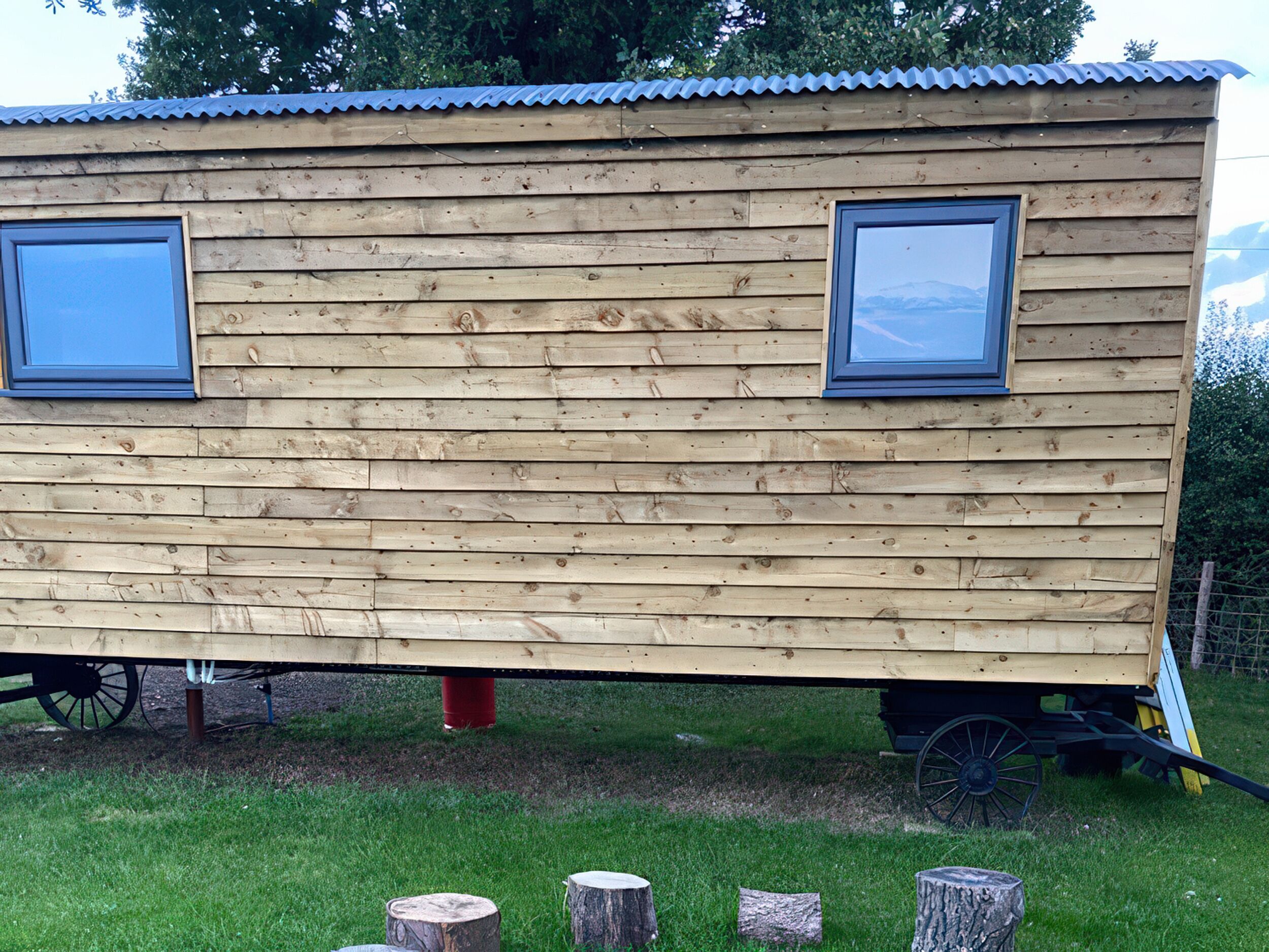 Une maison mobile en bois, dotée de deux fenêtres et montée sur un châssis de remorque.