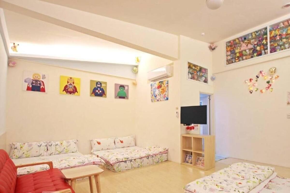 A child-friendly room with a sofa, a TV, and wall decorations including posters and a shelf with toys.
