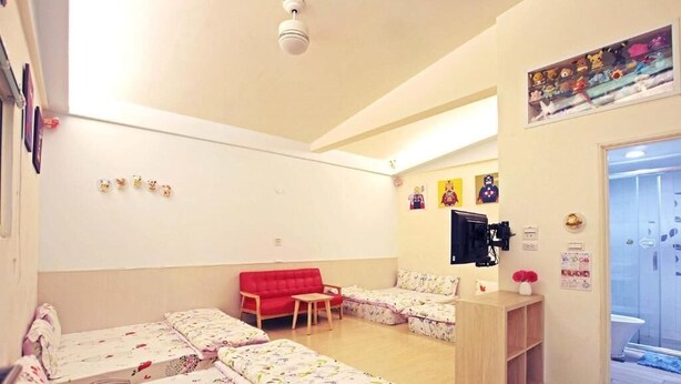 A room with a red sofa, a small table, and a patterned sofa set. There is a wall-mounted TV and a shelf with decorative items. - Wan-Yue B&B (Hengshan)
