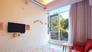 A bedroom with a bed, a TV, a window with a view of the outdoors, and a red chair. - Wan-Yue B&B (Hengshan)