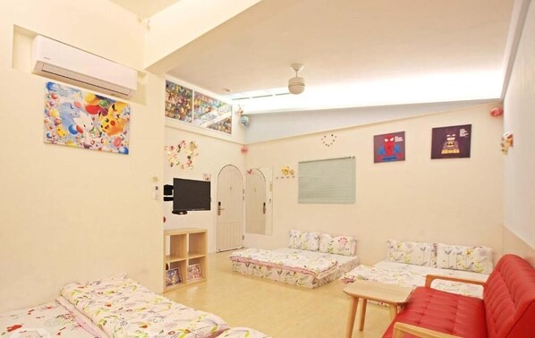 A child-friendly room with a bed, a red sofa, a TV, and wall decorations. - Wan-Yue B&B (Hengshan)