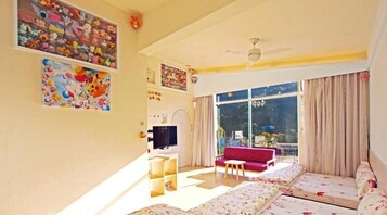 A living room with a red sofa, a television, and a large window with curtains.