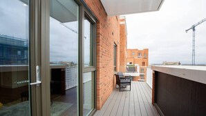 A balcony with a glass door, a table with chairs, and a view of surrounding buildings. - 2 Bed Flat - Sleeps 6 - Parking - Wifi (London)