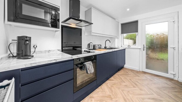 A modern kitchen with a built-in oven, a coffee machine, and a large window. - The Elphin Escape - 3 bedroom house (East Kilbride)