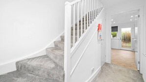 A staircase with carpeted steps and white railings leading to a door with a glass panel. - The Elphin Escape - 3 bedroom house (East Kilbride)